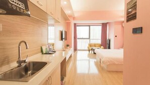 A modern hotel room with a kitchenette, a large window with curtains, a bed, and a TV. - Mango Hotel (Bengbu)