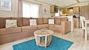 Ein gemütlicher Wohnbereich mit einer Couch, einem kleinen runden Tisch und einer Küche im Hintergrund.
