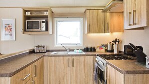 Eine moderne Küche mit Holzausstattung, einer Mikrowelle, einem Toaster, einer Spüle und einem Herd.