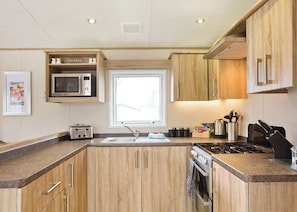 A modern kitchen with wooden cabinets, a microwave, a toaster, a sink, and a stove.