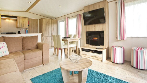 Ein modernes Wohnzimmer mit Sofa, Esstisch, Stühlen, Fernseher und Kamin.