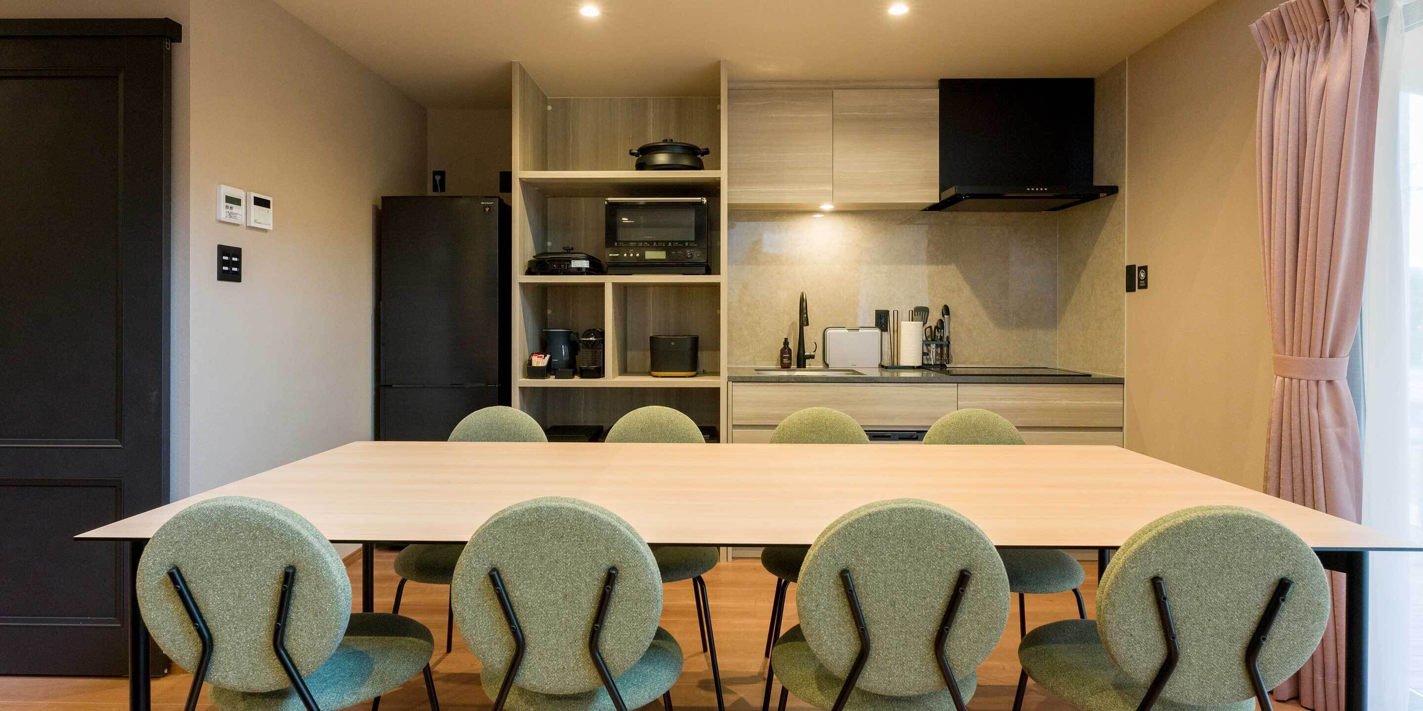 A modern kitchen with built-in appliances, a dining table with chairs, and a TV mounted above the counter.