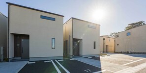 A parking lot with marked spaces and a building with a flat roof and large windows. - Rakuten STAY VILLA Kamogawa (Kamogawa)