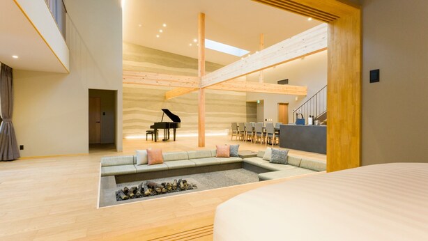 Uma sala de estar ampla com sofá seccional, um piano e um espaço para refeições.