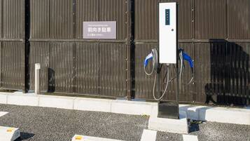 A parking area with a sign indicating front-end parking only, a charging station, and a metal fence.