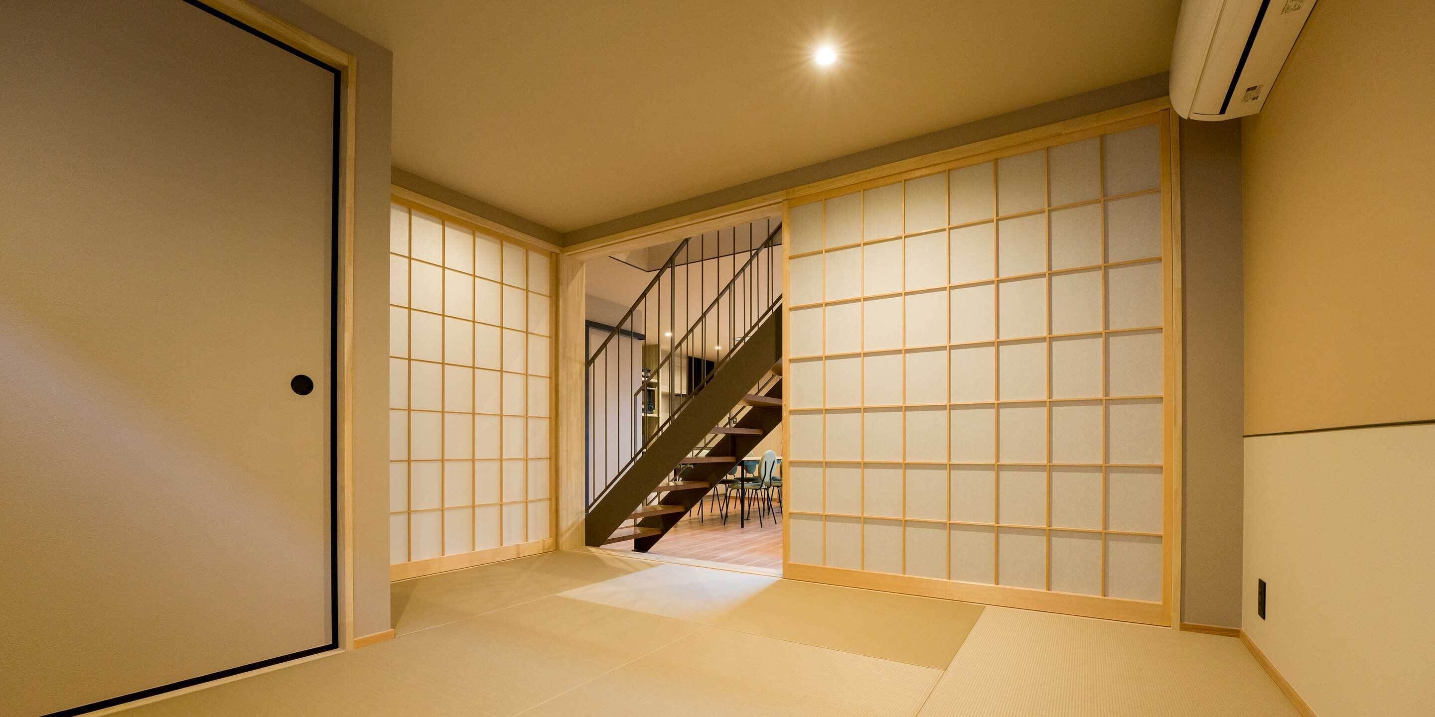 Ein traditionelles japanisches Interieur mit Tatami-Böden, Schiebetüren und einer Treppe.