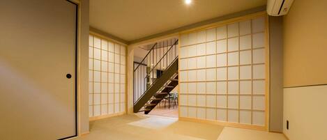 Ein traditionelles japanisches Interieur mit Tatami-Böden, Schiebetüren und einer Treppe.