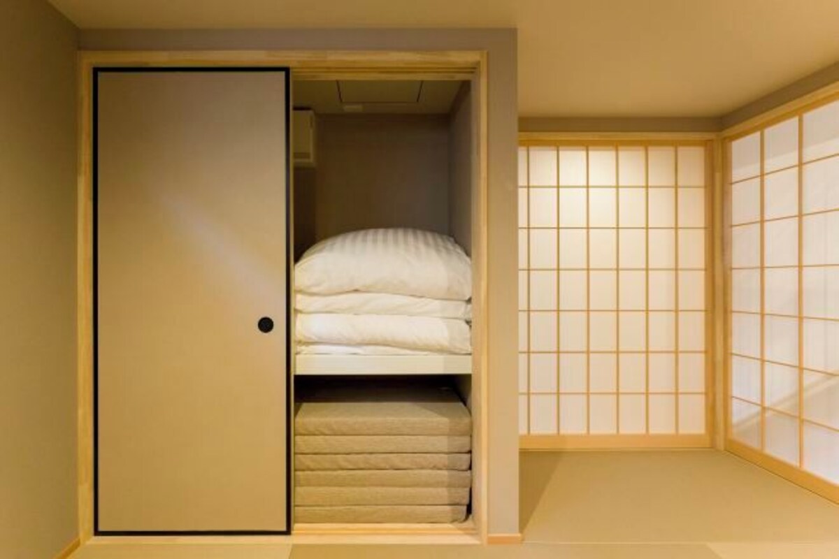 A compact room with a bed, a wardrobe, and a sliding shoji screen.