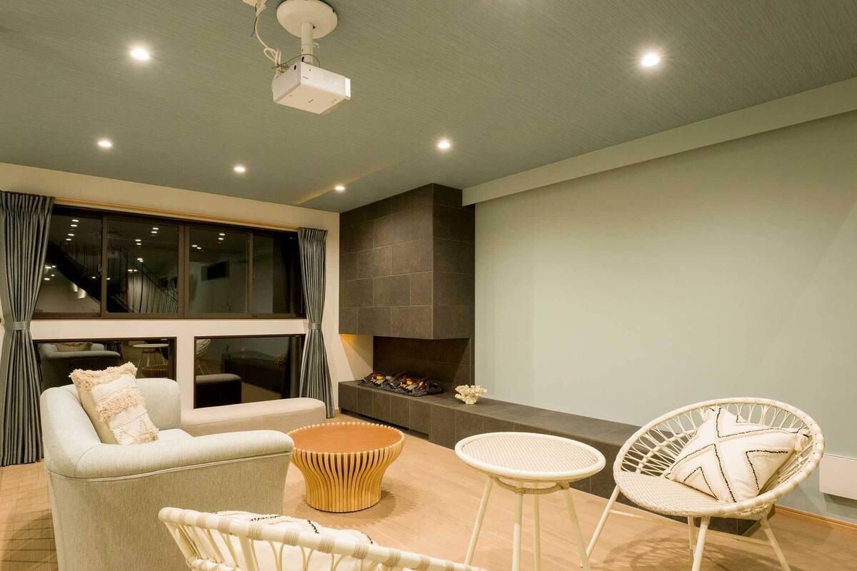 A modern living room with a sofa, two chairs, a coffee table, and a fireplace.