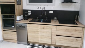 Una cocina moderna con horno empotrado, lavavajillas, cafetera y fregadero.