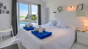A hotel room with a large bed, a chair, a bedside table with a lamp, and a view of a swimming pool. - Villa  with private pool in Moraira, Costa Blanca, Spain for 4 persons (Moraira)