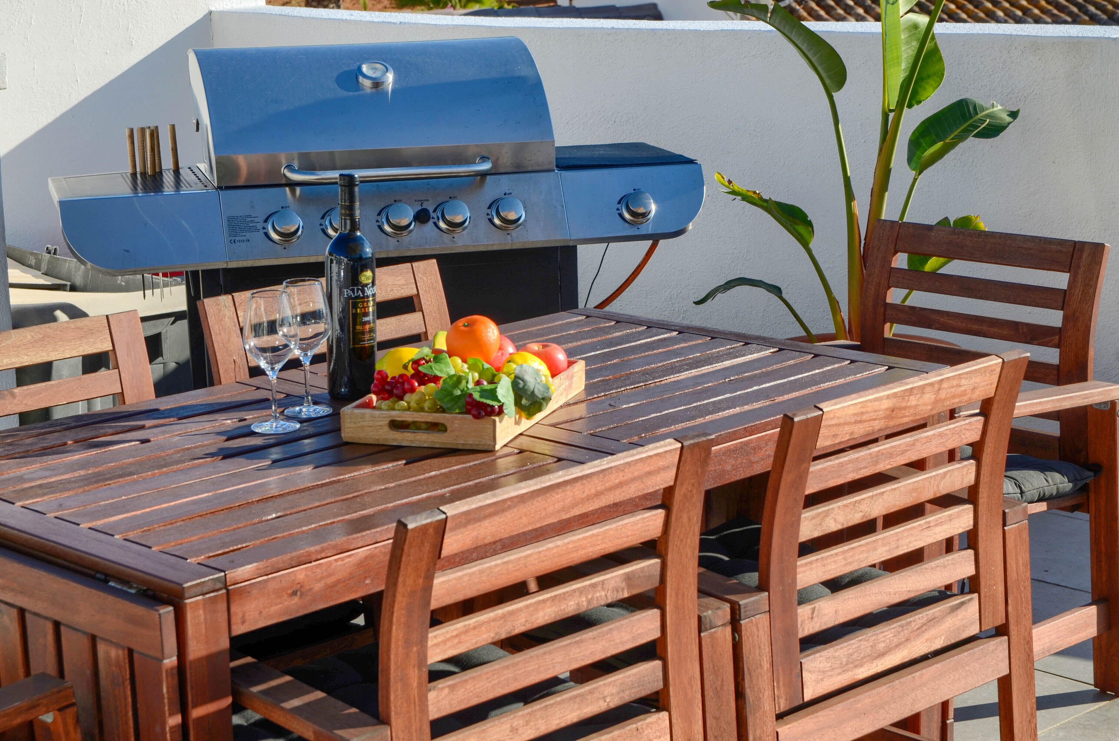 A wooden table with a grill and a fruit basket.