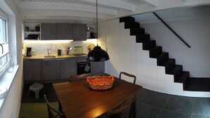 A modern kitchen with a dining area, a staircase, and a small stool. - Bauernhäusle - the house with a beautiful garden (Friedrichshafen)