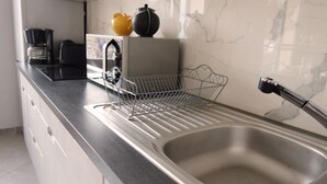A kitchen with a stainless steel sink, a dish rack, a coffee maker, and a kettle on the counter. - Two bedroom apartment in the heart of Vaison la Romaine (Vaison-la-Romaine)