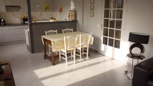 A dining area with a table and chairs, a kitchen in the background, and a door with glass panels. - Two bedroom apartment in the heart of Vaison la Romaine (Vaison-la-Romaine)