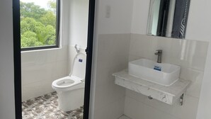 A bathroom with a toilet, a sink, and a mirror. - Moon house villa (Da Nang)