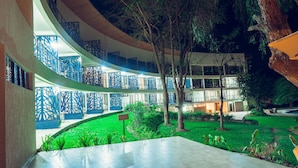 Un vestíbulo de hotel de varios niveles con un patio central, con un diseño moderno que incluye paneles decorativos azules y un jardín cuidado.