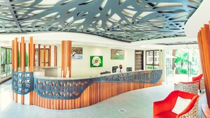 Zona de recepción con un mostrador curvo de madera, una recepcionista y un diseño de techo moderno.