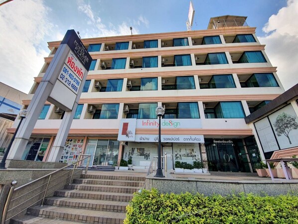 Um edifício de vários andares com uma placa de destaque 'Infinity Design', apresentando uma escadaria que leva à entrada.