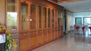 A spacious hotel lobby with a large wooden cabinet, a reception desk, and red bar stools. - The Popular place (Bang Phli)