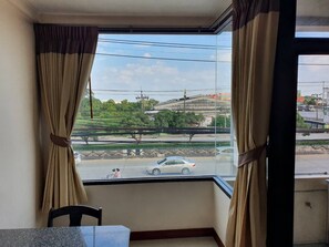 Quarto com uma janela grande, cortinas, uma mesa e uma cadeira.