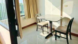 A room with a glass table, two chairs, a window with curtains, and a view of greenery outside. - The Popular place (Bang Phli)