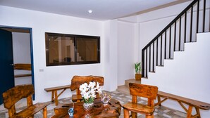 A dining area with a wooden table and benches, a window, and a staircase.