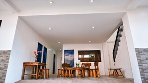 A modern interior with a wooden dining set, a blue door, and a staircase.