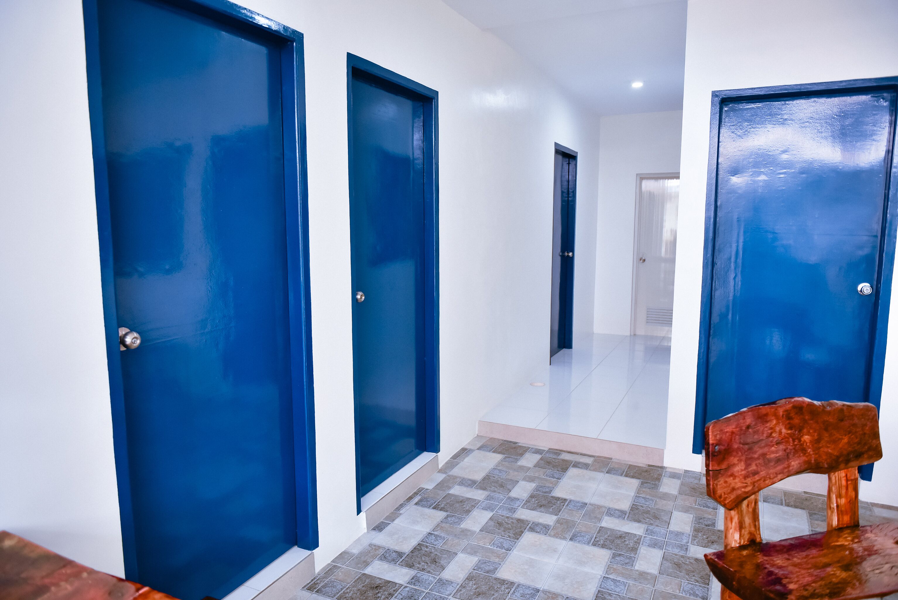 A hallway with blue doors and a checkered floor.