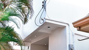 A modern building with a covered outdoor area, a small window, and visible electrical wiring.