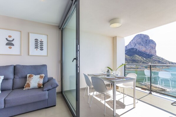 A balcony with a dining table, chairs, and a sofa with cushions.