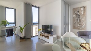 A modern living room with a flat-screen TV, a glass coffee table, and a comfortable seating area. - Apartamento Bernia al Mar by Costa CarpeDiem (Calpe)