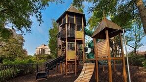 A playground with a wooden slide, a climbing structure, and a lookout tower.