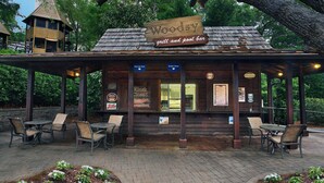 A wooden structure labeled "Woodsy Grill and Pool Bar" with outdoor seating and a covered patio area.