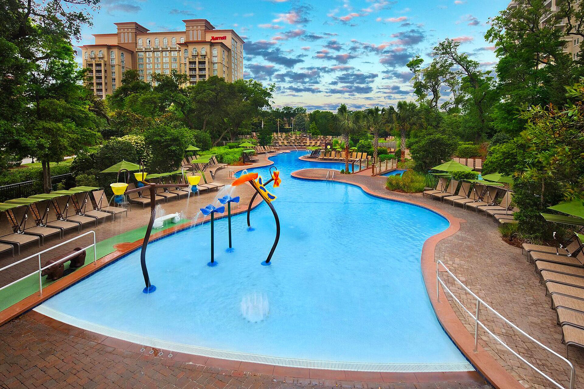 Ein Swimmingpool mit Wasserrutsche, Liegestühlen und einem Marriott Hotel im Hintergrund.