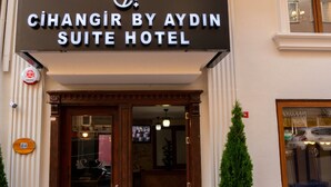 Ingången till Cihangir by Ayrdin Suite Hotel har ett svart solskydd, en trädörr och ett litet utomhusområde med sittplatser.