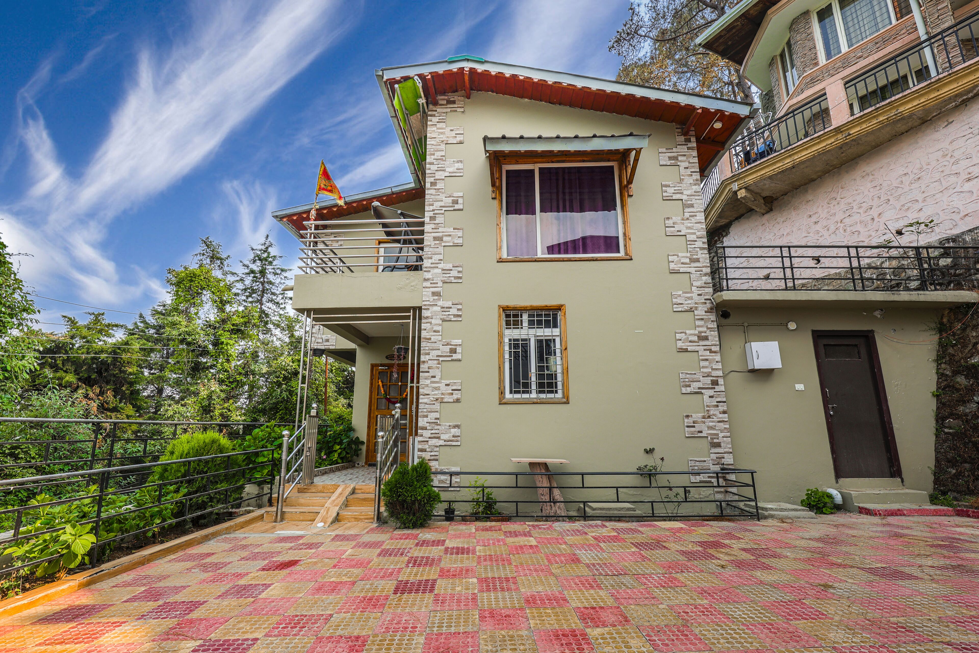 A two-story building with a balcony, a flag, and a tiled patio area.