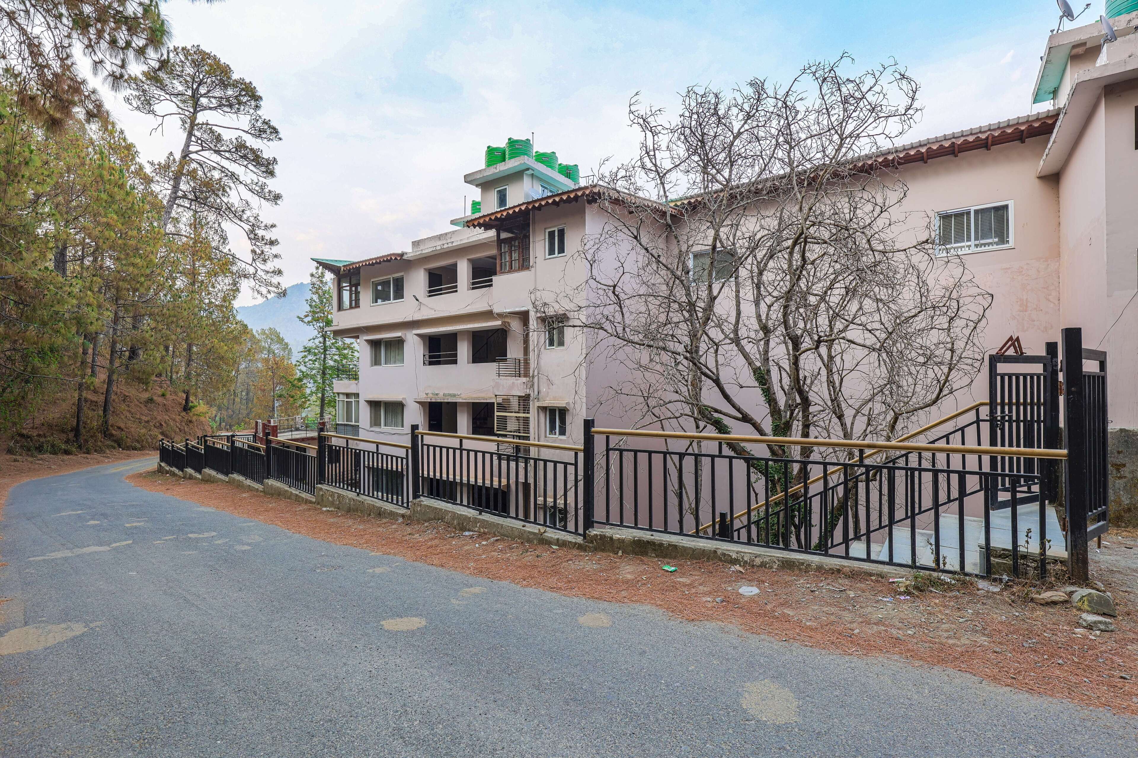 A multi-story residential building with a gated entrance, a staircase, and a paved road with directional arrows.