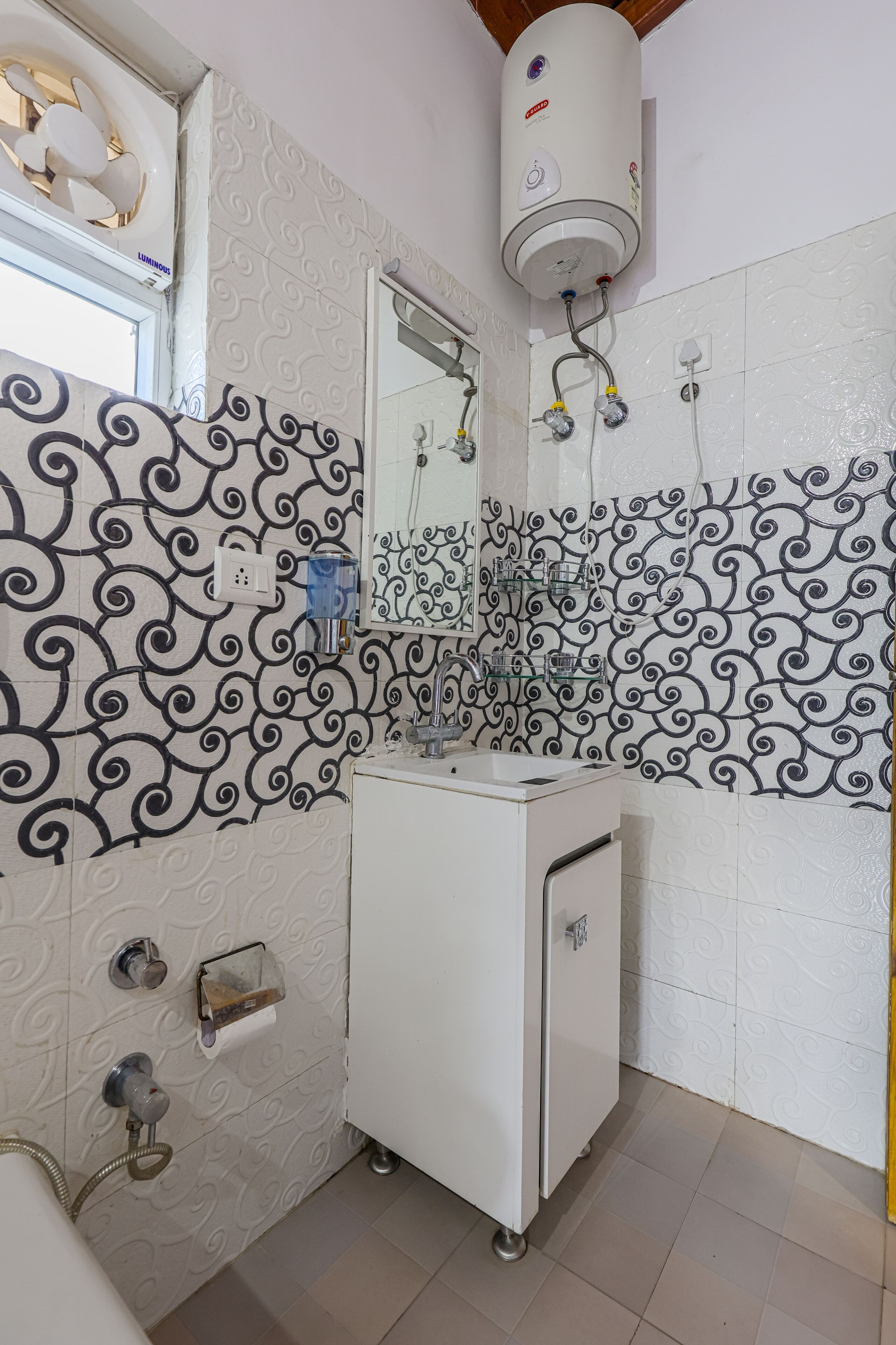 A bathroom with a white sink, a mirror, a towel rack, and a wall-mounted heater.