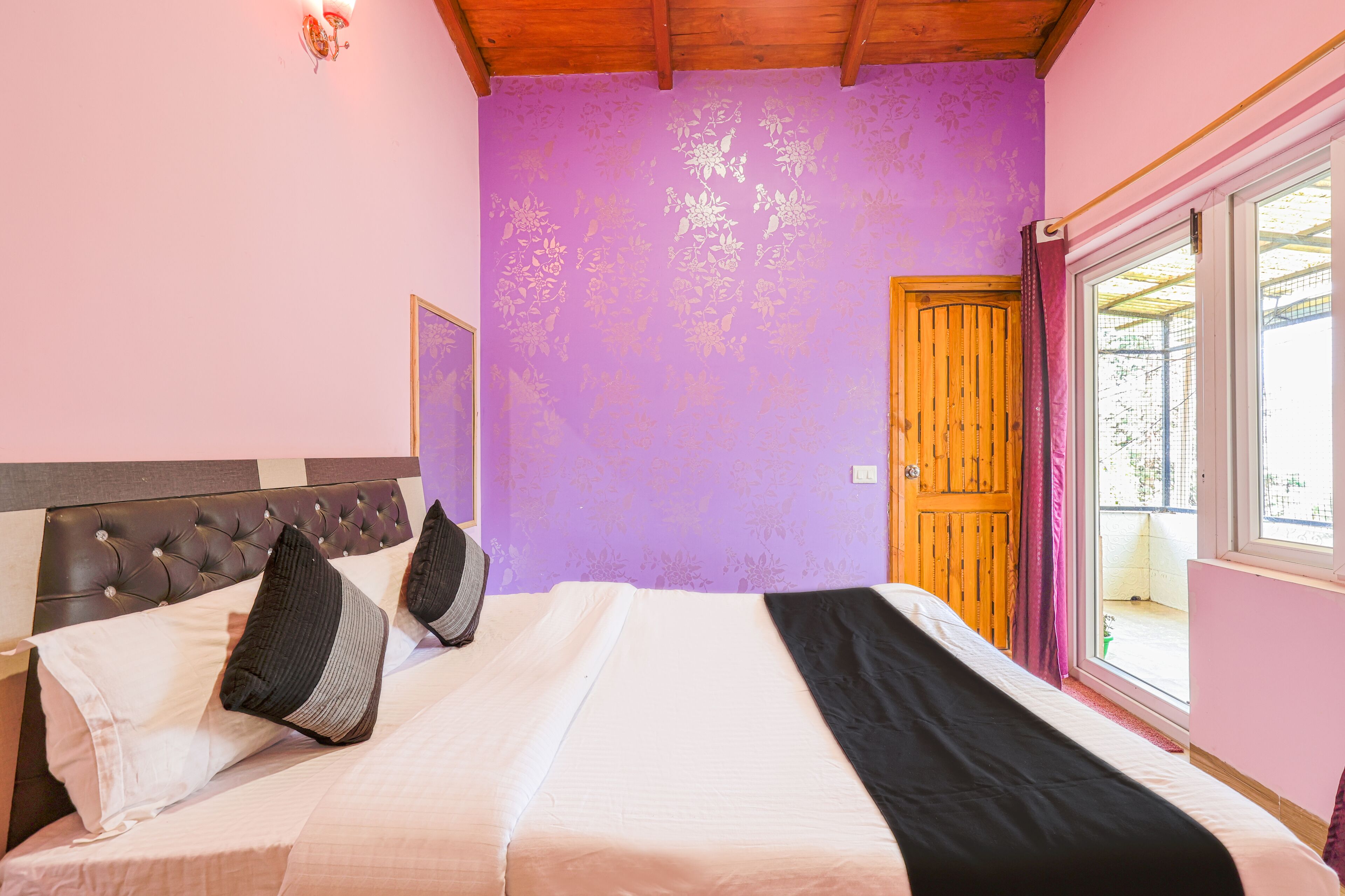 A bedroom with a bed, a wooden door, and a window.