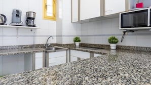 A kitchen with granite countertops, a sink, a microwave, and a coffee maker. - Miramar Nautic by Interhome (Salou)