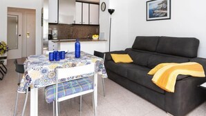 Ein gemütlicher Wohnraum mit Esstisch, Sofa und Küchenzeile.