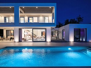 A modern two-story house with a swimming pool in front.