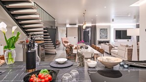 A modern kitchen with a marble countertop, a dining area with a long table, and a staircase leading to an upper level. - Villa Sonia by Interhome (Labin)