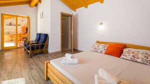 Una camera da letto con un letto di legno, una sedia e un bagno raggiungibile tramite una porta.
