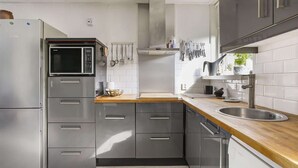 Eine moderne Küche mit Edelstahlgeräten, Holz Arbeitsplatten und einem eingebauten Geschirrspüler.