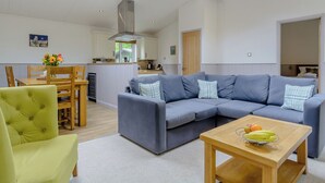 A modern living room with a sectional sofa, a dining table, and a kitchen in the background.