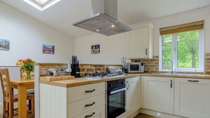 A kitchen with a central island, a stove, microwave, and a window with a view.
