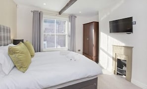 Un dormitorio con una cama grande, un armario, un televisor y una chimenea.
