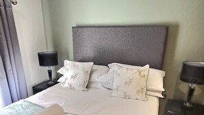 A neatly made bed with a green bedspread, two rolled towels, and pillows with a deer pattern. There are two bedside tables with lamps. - The Bingham, Fossgate  Apartments Central York (York)